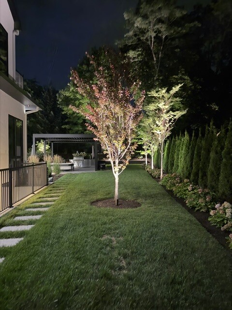 Stepping-stone path and tree lighting across a residential lawn in Newton, MA.