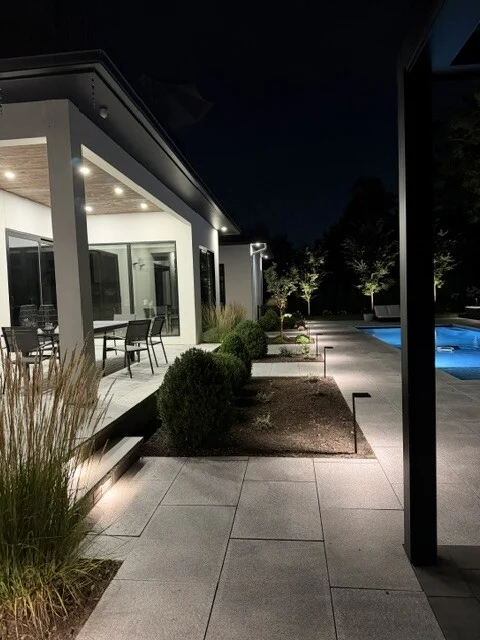 Recessed walkway lighting beside a pool and covered patio in Newton, MA.